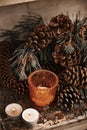 Cones and pine tree brunch arranged with candles on a vintage cabinet