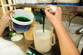 Confectioner in chef uniform is adding mint essence with spatula. Woman adds a mint extract and a concentrate to ice cream.