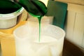 Confectioner in chef uniform is adding mint essence with spatula. Woman adds a mint extract and a concentrate to ice cream.