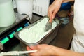 Confectioner in chef uniform is working at ice cream factory. Woman is decorations of italian creamy mint ice cream flavors.