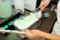 Confectioner in chef uniform is working at ice cream factory. Woman is decorations of italian creamy mint ice cream flavors.