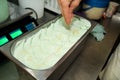 Confectioner in chef uniform is working at ice cream factory. Woman is decorations of italian creamy mint ice cream flavors.