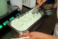 Confectioner in chef uniform is working at ice cream factory. Woman is decorations of italian creamy mint ice cream flavors.