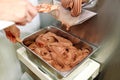 Confectioner in chef uniform is working on ice cream maker machine. Producing black chocolate ice cream flavors.