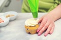 Confectioner decorate cupcakes with cream cheese  close up. Pastry chef using a pastry bag. Sweet desserts. Woman cooking cakes Royalty Free Stock Photo