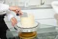 confectioner evens out cake, covers with white chocolate. Home production Royalty Free Stock Photo