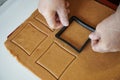 The confectioner forms gingerbread cookies using an original rectangular cutting. Woman& x27;s hands in protective gloves Royalty Free Stock Photo