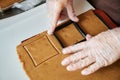 The confectioner forms gingerbread cookies using an original rectangular cutting. Woman& x27;s hands in protective gloves Royalty Free Stock Photo