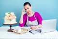 Confectioner housewife pastry-cook businesswoman looks disappointed at the white two-tiered wedding cake with fresh