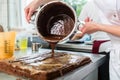 Confectioner putting chocolate as frosting on cake