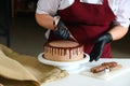 Confectioner process chocolate cake on table. The process of decorating the cake with liquid chocolate. The process of making the Royalty Free Stock Photo