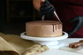 Confectioner process chocolate cake on table. The process of decorating the cake with liquid chocolate. The process of making the Royalty Free Stock Photo