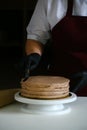 Confectioner process chocolate cake on table. The process of decorating the cake with liquid chocolate. The process of making the Royalty Free Stock Photo