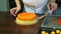 Confectioner puts cheesecake with orange glaze on almond interlayer