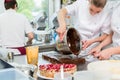 Confectioner putting chocolate as frosting on cake