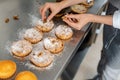 Confectioner putting nuts on little cakes