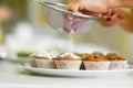 Confectioner sprinkles freshly baked muffins with icing sugar. Sweet pastries, recipes, cooking Royalty Free Stock Photo