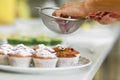 Confectioner sprinkles freshly baked muffins with icing sugar. Sweet pastries, recipes, cooking Royalty Free Stock Photo