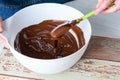 Confectioner tempering chocolate with a spatula in a white bowl