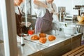 Confectioner ties sleeve with cream teaching trainee at table with croissants in bakery shop