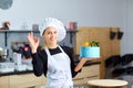 A confectioner woman with a cake in her hands in the kitchen.