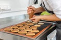 Confectioner woman using pastry bag to put cream on top of cookies