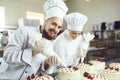 Confectioners with a bag for the cream will decorate the cake.