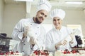 Confectioners with a bag for the cream will decorate the cake. Royalty Free Stock Photo