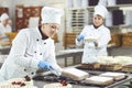 A confectioners squeezes liquid cream from a pastry bag.