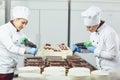 A confectioners squeezes liquid cream from a pastry bag.