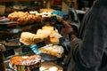 Confectionery customer, client in sweet-shop, pastry-shop. Back view of young woman choosing cake desserts from display Royalty Free Stock Photo