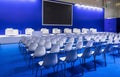 Conference Meeting Room, Row of White Chairs, with Stage and Empty Screen Royalty Free Stock Photo
