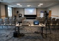Conference room setup with rows of gray chairs facing a large projection screen displaying a Royalty Free Stock Photo