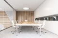 Conference room with white chairs and wooden table, glass doors white walls