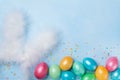 Confetti, bunny ears and colorful Easter eggs on blue table top view. Funny Easter greeting card. Copy space for text. Royalty Free Stock Photo