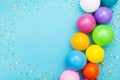 Confetti and colorful balloons for birthday party on blue table top view. Flat lay style. Royalty Free Stock Photo
