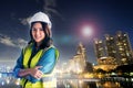 Female Civil Engineer with safety equipment with night modern city in the background for City Development cocept