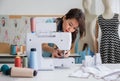 Confidence female dressmaker with a sewing machine in her tailor shop