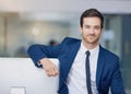 Confidence and success are mutually exclusive. Portrait of a young businessman leaning on his pc in the office.