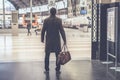 Confident adult man standing with travel bag at the hall of railway station and looking his train. Royalty Free Stock Photo