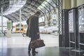 Confident adult man standing with travel bag at the hall of railway station and looking train schedule.Visual effects. Royalty Free Stock Photo