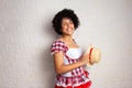 girl with curly hair wearing traditional junina costume holding hat with big smile. Brazilian June