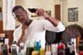 Confident african american male winemaker inspecting quality of red wine, checking it in wine store