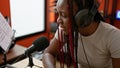 Confident african american woman reporter in braids, speaking on air at an indoor music studio, broadcasting news via radio, with