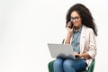 Confident African-American woman in smart casual wear using laptop and talking on the smartphone Royalty Free Stock Photo
