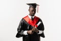 Confident african man bachelor in graduation robe and cap on white background. Happy and funny african graduate man Royalty Free Stock Photo
