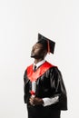 Confident african man bachelor in graduation robe and cap on white background. Happy and funny african graduate man Royalty Free Stock Photo