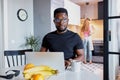 Confident african man work on laptop at home while wife is busy in the kitchen Royalty Free Stock Photo