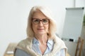 Confident aged businesswoman wearing glasses looking at camera,