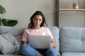 Confident Arabian woman sitting on couch with laptop, working online